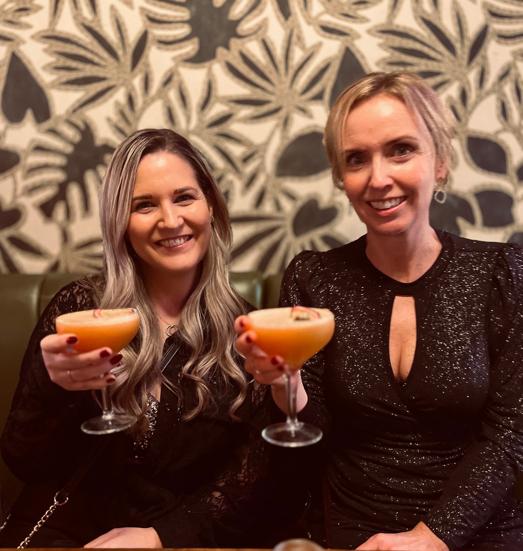 Two members raising cocktails in the lounge booth